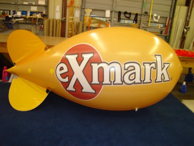 Yellow helium advertising blimp custom printed with the eXmark company logo